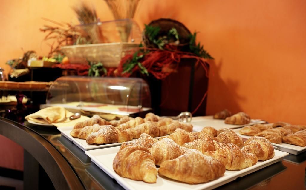 A buffet table with various pastries, including croissants and other baked goods, and a glass display case with additional items.