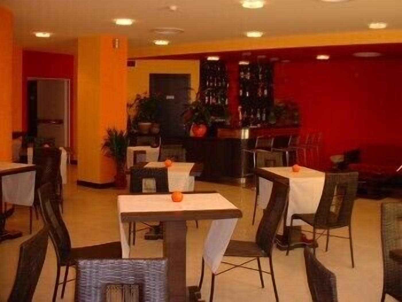 Un restaurant avec des tables et des chaises, un comptoir où figure le menu, et un mur rouge.