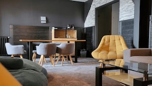 A modern living room with a sofa, armchairs, a glass coffee table, and a dining area with a wooden table and chairs.