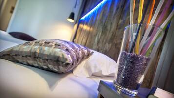 A bed with a patterned pillow and a glass container with colorful straws.