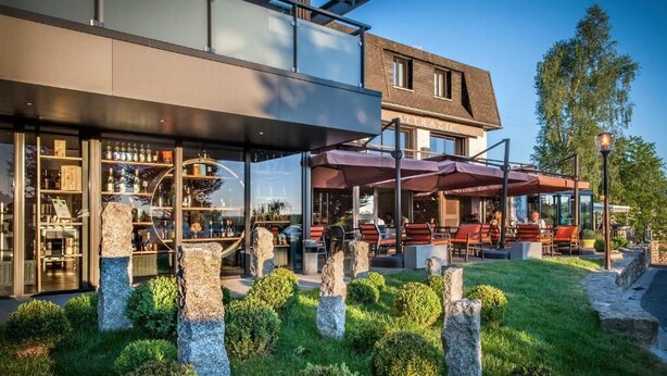 A modern building with a glass storefront and outdoor seating area.