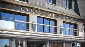 An outdoor seating area with tables and orange chairs at the 'CYRIL ATTRAZIC' restaurant.