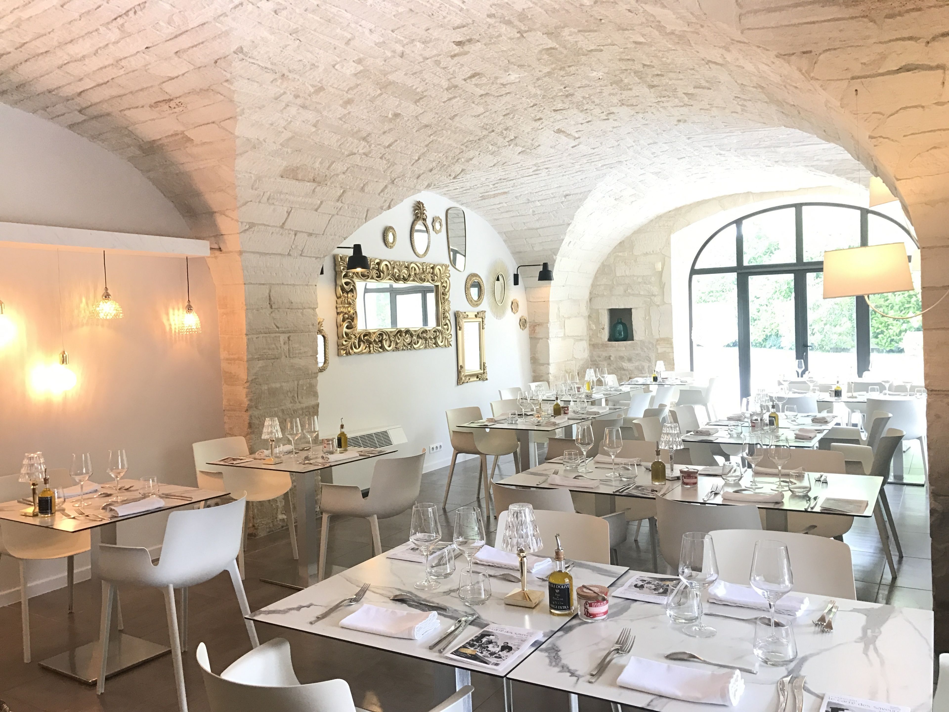 Ein Restaurant mit mehreren Esstischen, das eine Steinwand und eine gewölbte Decke zeigt.