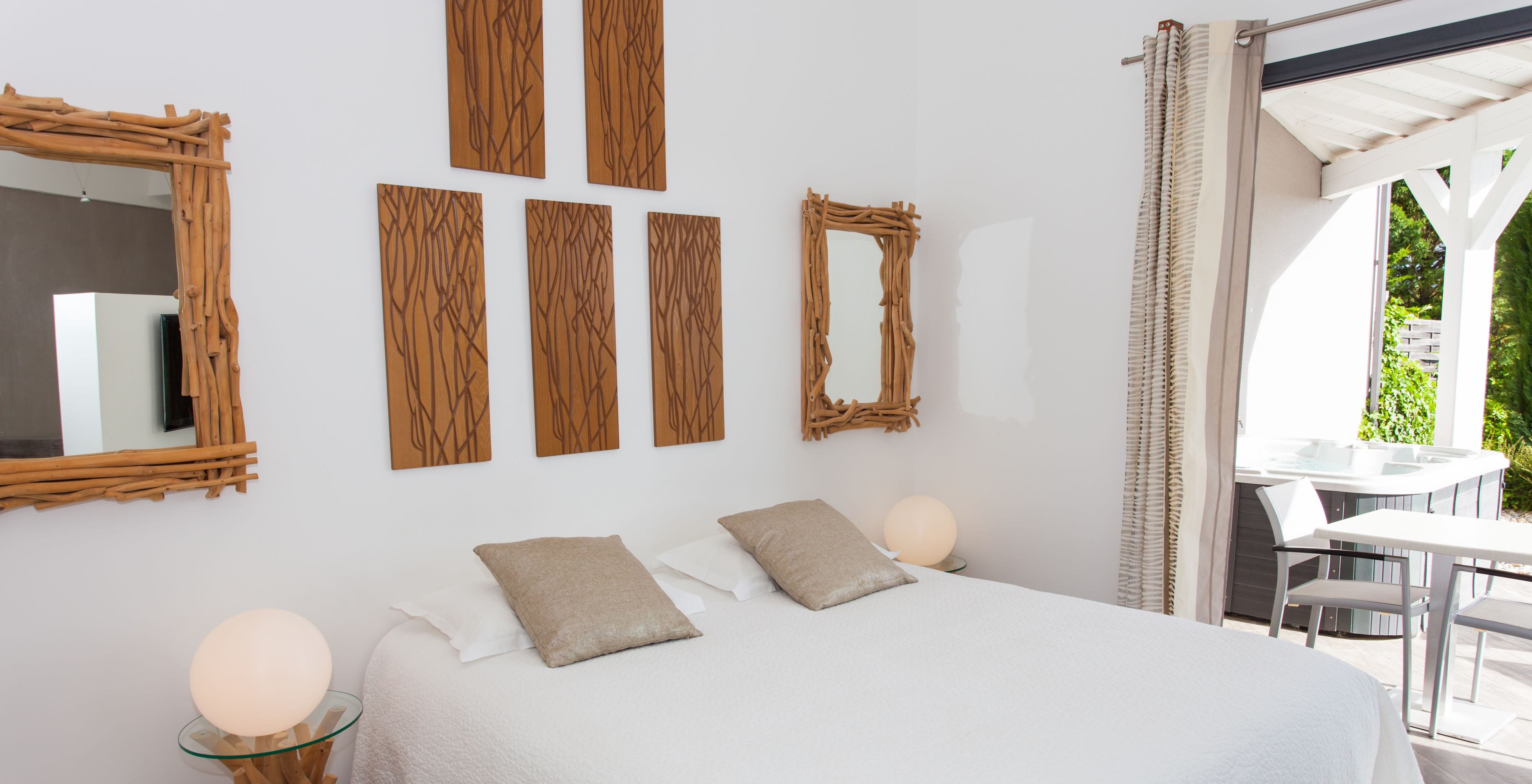 Quarto com cama, duas luminárias de cabeceira, um espelho grande e quatro painéis de madeira fixados na parede.