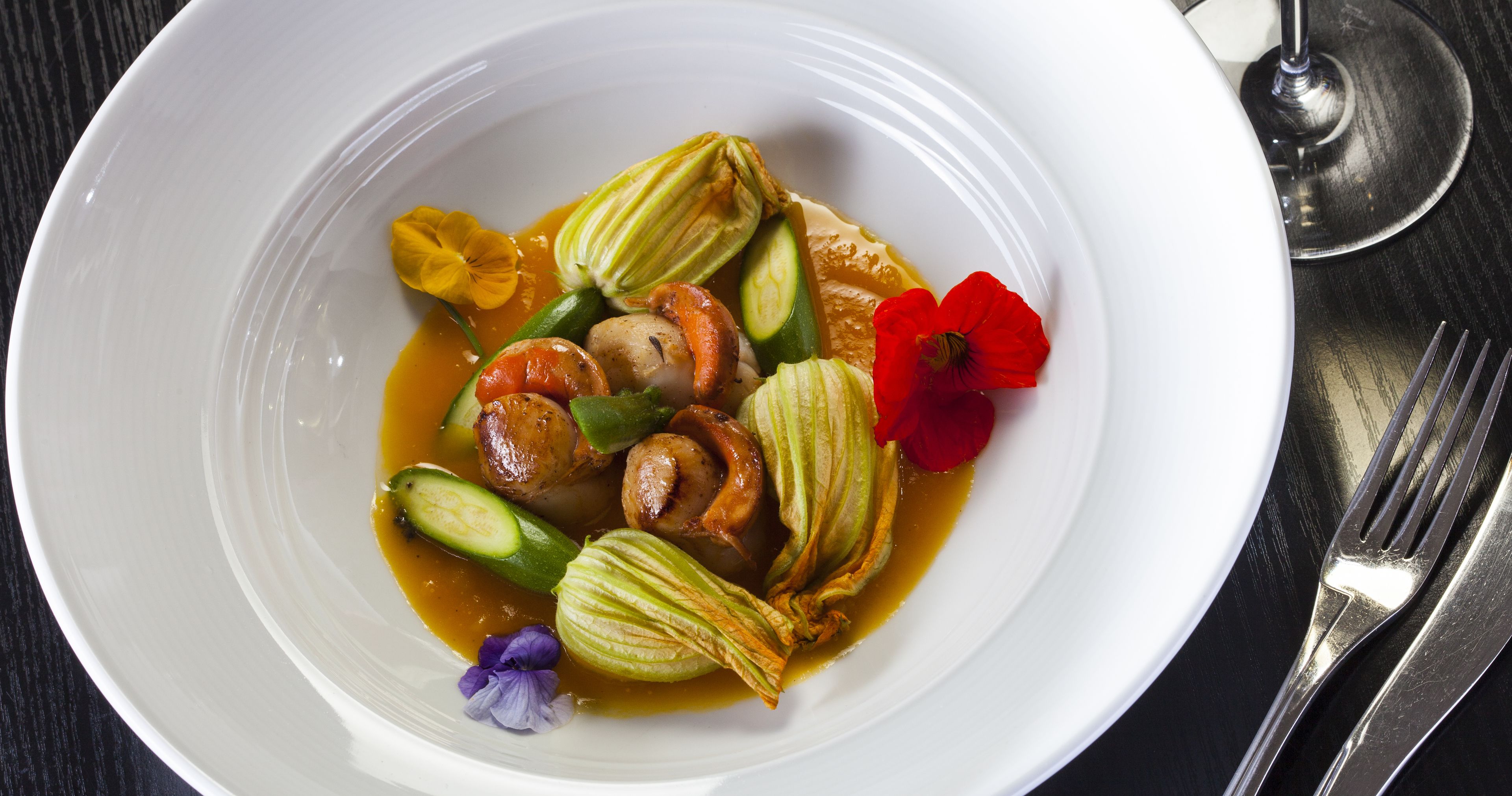 A white plate with a dish containing vegetables and flowers.