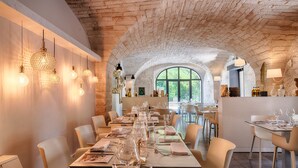 A restaurant with a long table set for dining, arched brick ceiling, and hanging pendant lights. - Le Mas du Terme (Barjac)