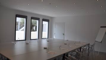 A conference room with a long table, clear chairs, and a whiteboard.