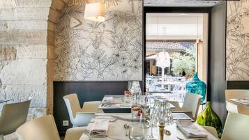 A restaurant with a modern interior, featuring a brick wall, a floral mural, and a view of the outdoor seating area.