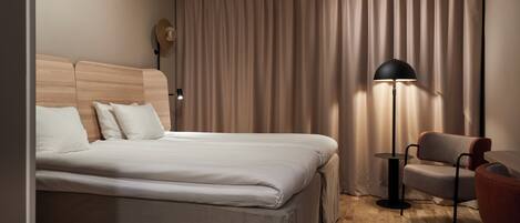 Una habitación de hotel con una cama, una silla, una lámpara y una cortina.