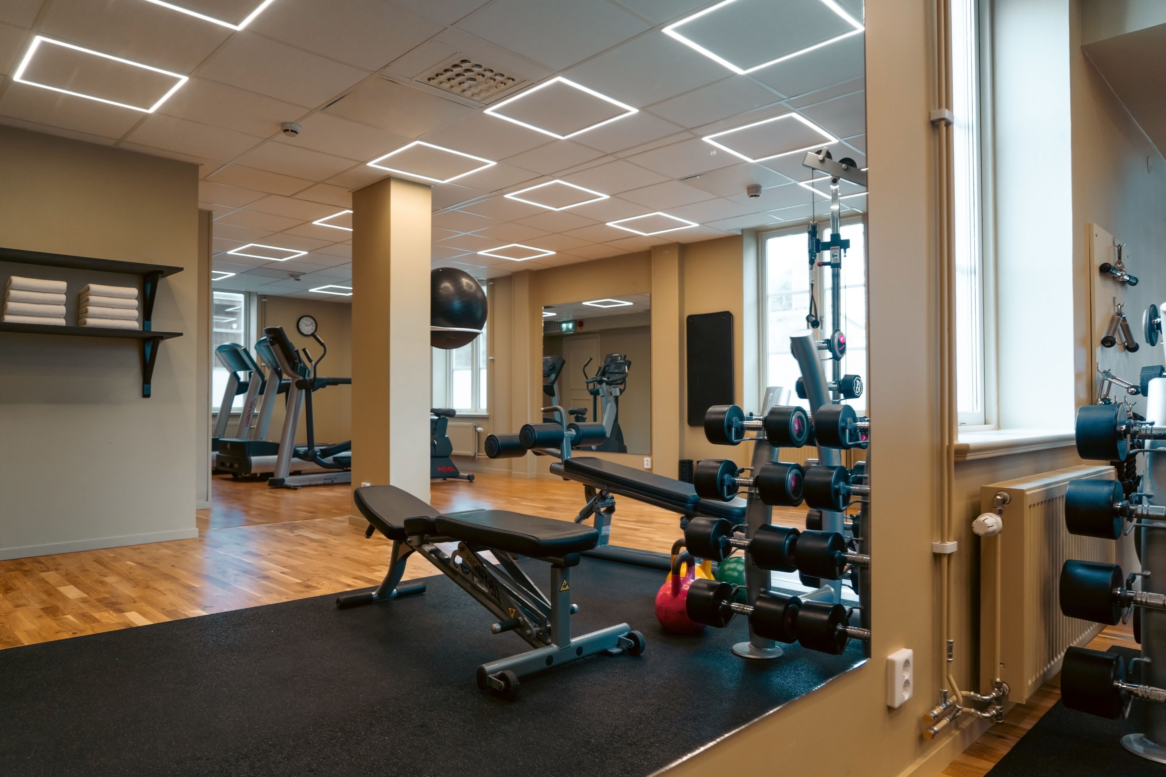 A gym with exercise equipment, a treadmill, and a mirror.