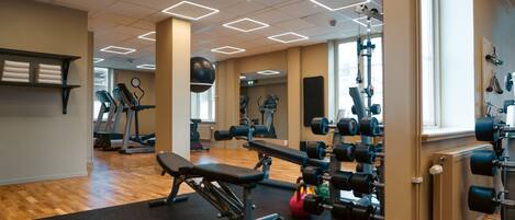 Un gimnasio con equipo de ejercicio, una cinta de correr y un espejo.