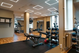 Un gimnasio con equipo de ejercicio, una cinta de correr y un espejo.