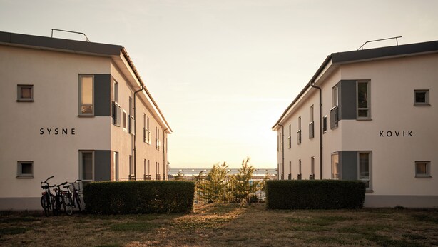 Two adjacent buildings labeled 'SYSNE' and 'KOVIK' with bicycles parked outside.