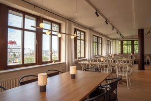A spacious dining area with large windows, multiple tables, and chairs.
