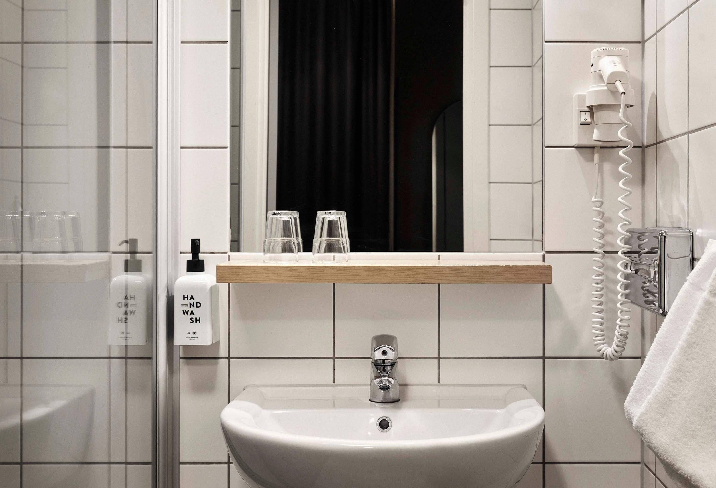 A bathroom with a sink, mirror, and hand soap dispenser.