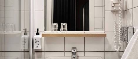 A bathroom with a sink, mirror, and hand soap dispenser.