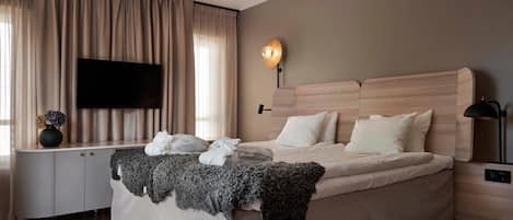 Un dormitorio moderno con una cama grande, un televisor de pantalla plana, una mesita de noche y una lámpara.