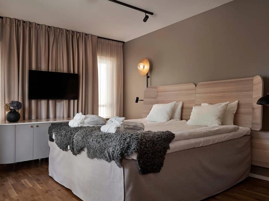 Un dormitorio moderno con una cama grande, un televisor de pantalla plana, una mesita de noche y una lámpara.