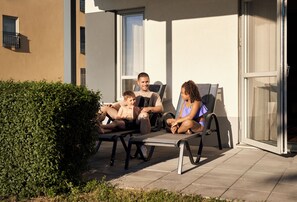 A patio area with outdoor seating, a hedge, and a building with windows and a door. - Quality Hotel Visby (Visby)