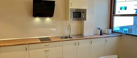 A modern kitchen with a microwave, sink, and a window with a view of buildings.