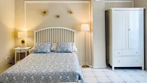 A bedroom with a bed, bedside lamps, a wardrobe, and decorative wall sconces. - Hi Valencia Cánovas (Valencia)