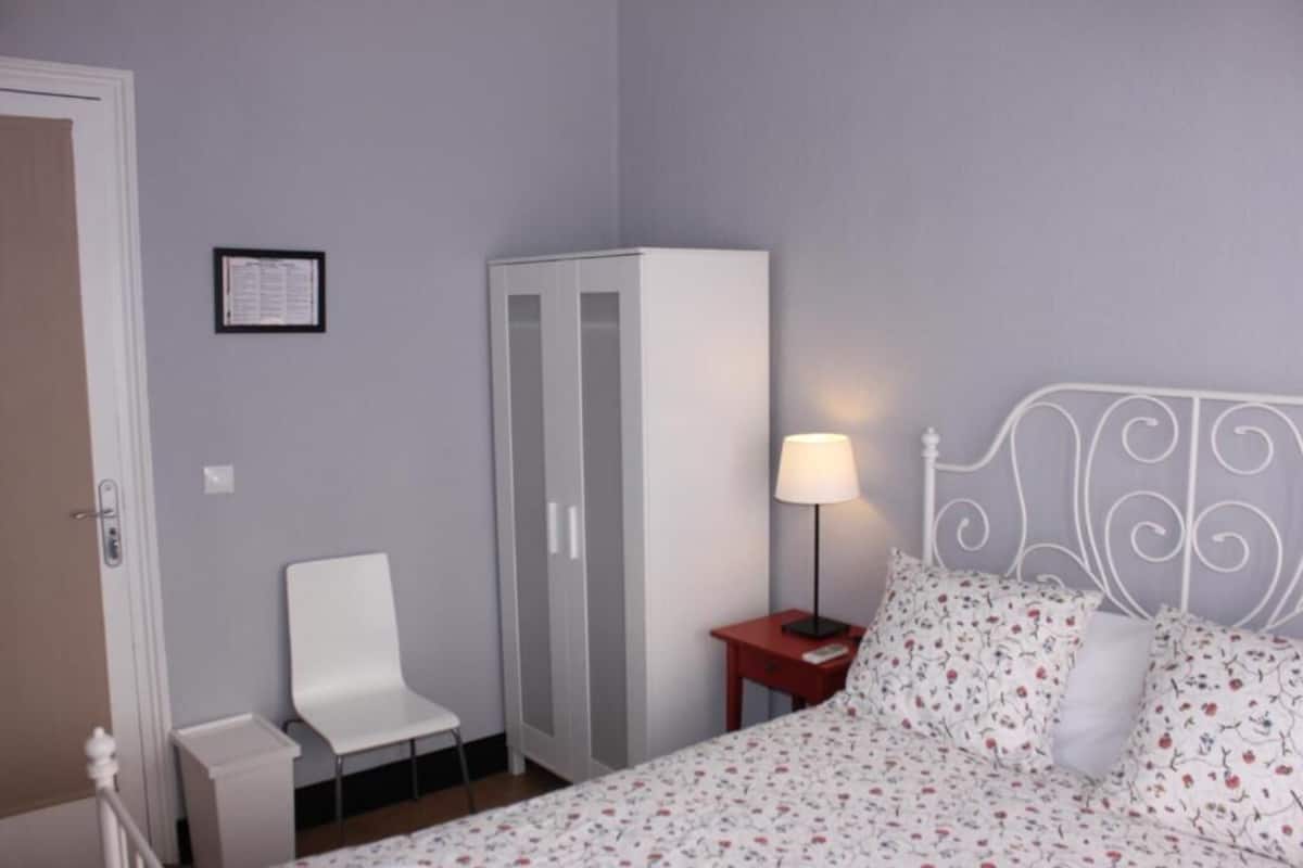 Cubrecamas, muebles diferentes y tabla de planchar con plancha