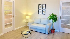 A living room with a white sofa, a round coffee table, a floor lamp, and a potted plant. - Hi Valencia Cánovas (Valencia)
