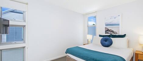 Un dormitorio con una cama, una ventana, una mesita de noche y una lámpara de pared.
