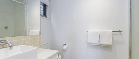 A modern bathroom with a white sink, mirror, and shower.