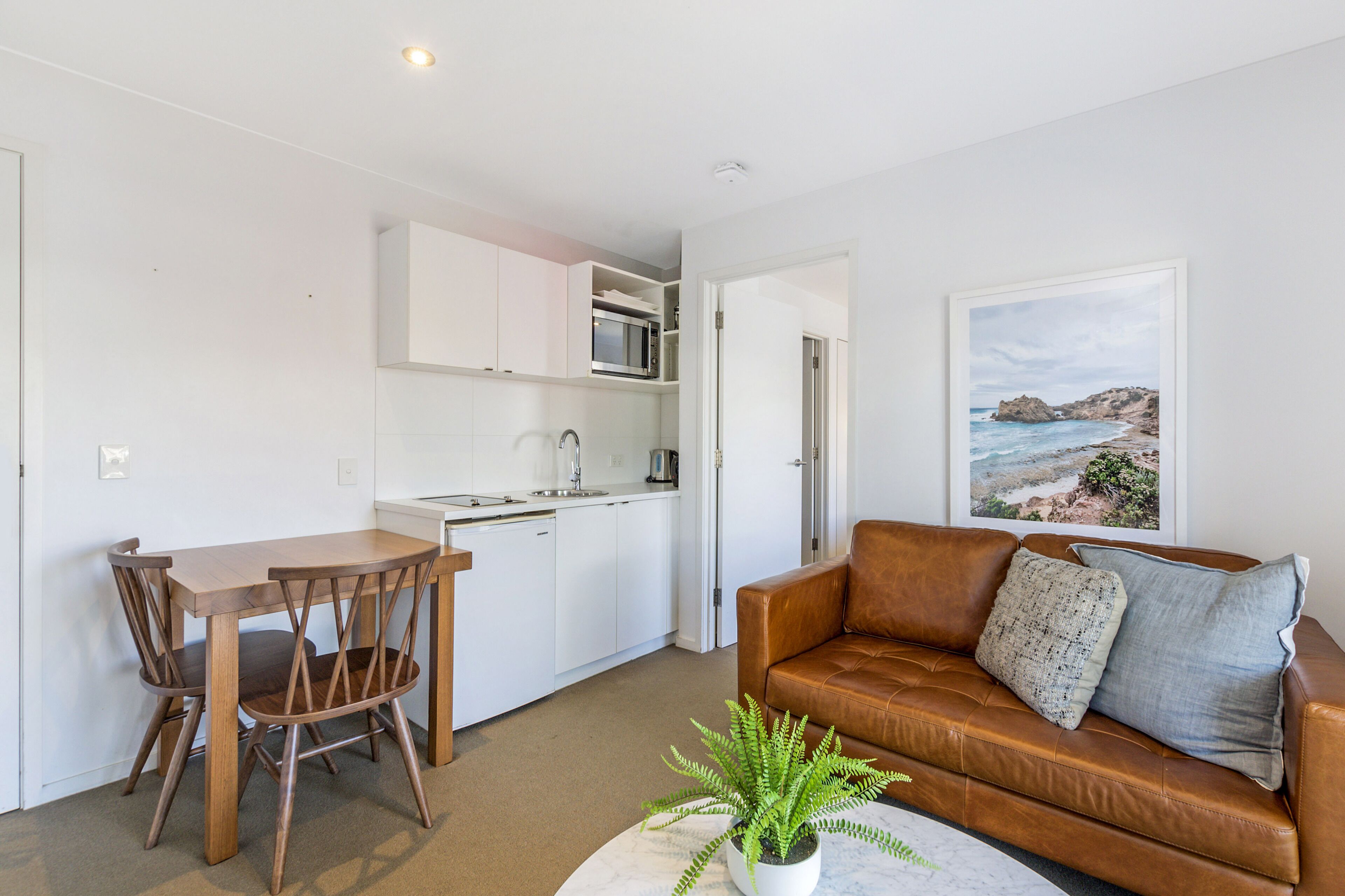 A compact living space with a kitchenette, a dining area, and a seating area with a view of the sea.