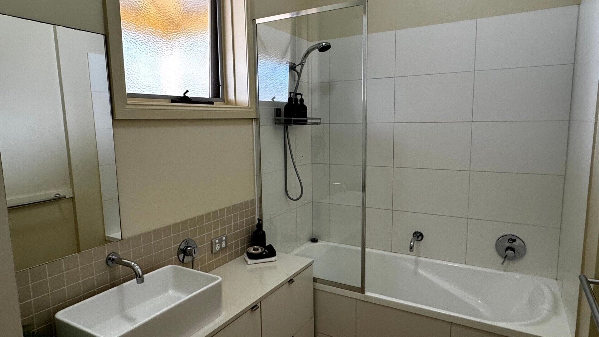A bathroom with a shower, a sink, and a bathtub.