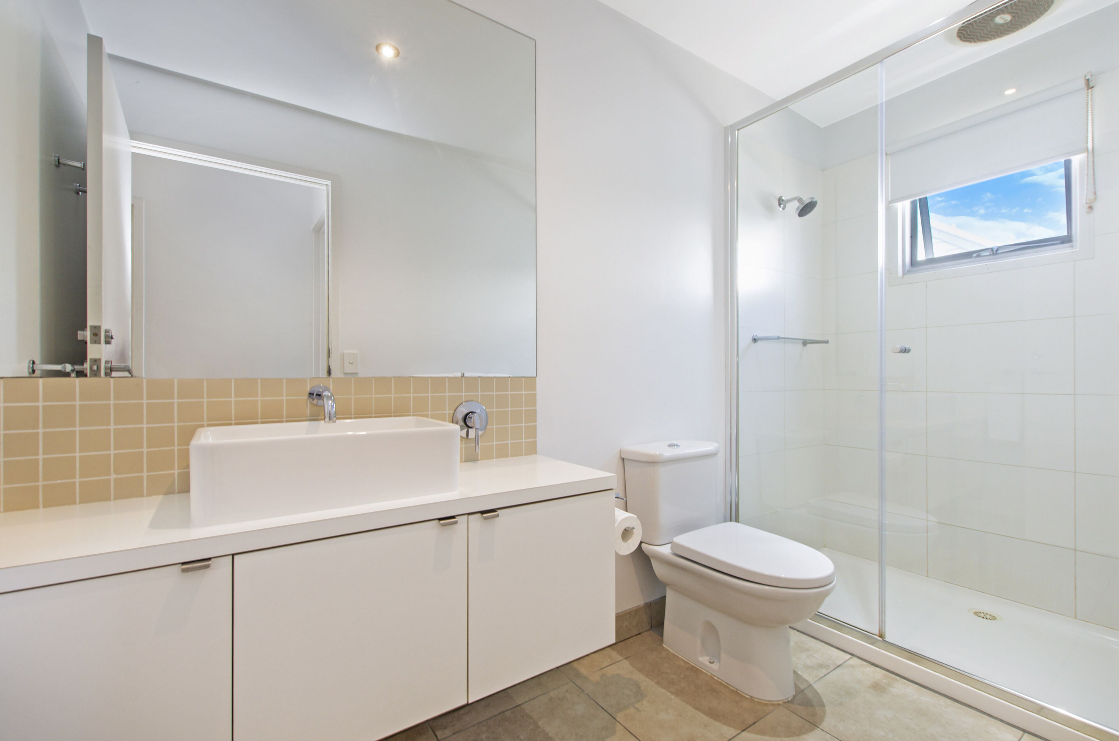 A modern bathroom with a glass shower enclosure, a white sink, and a toilet.