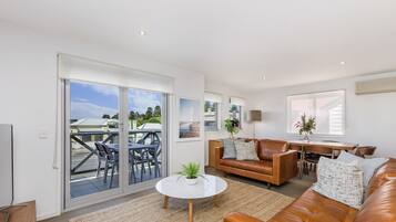 A modern living room with a leather sofa, a round coffee table, and a dining area with a table and chairs.