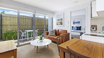 A modern living space with a dining area, a kitchen, and a sliding glass door leading to a backyard.