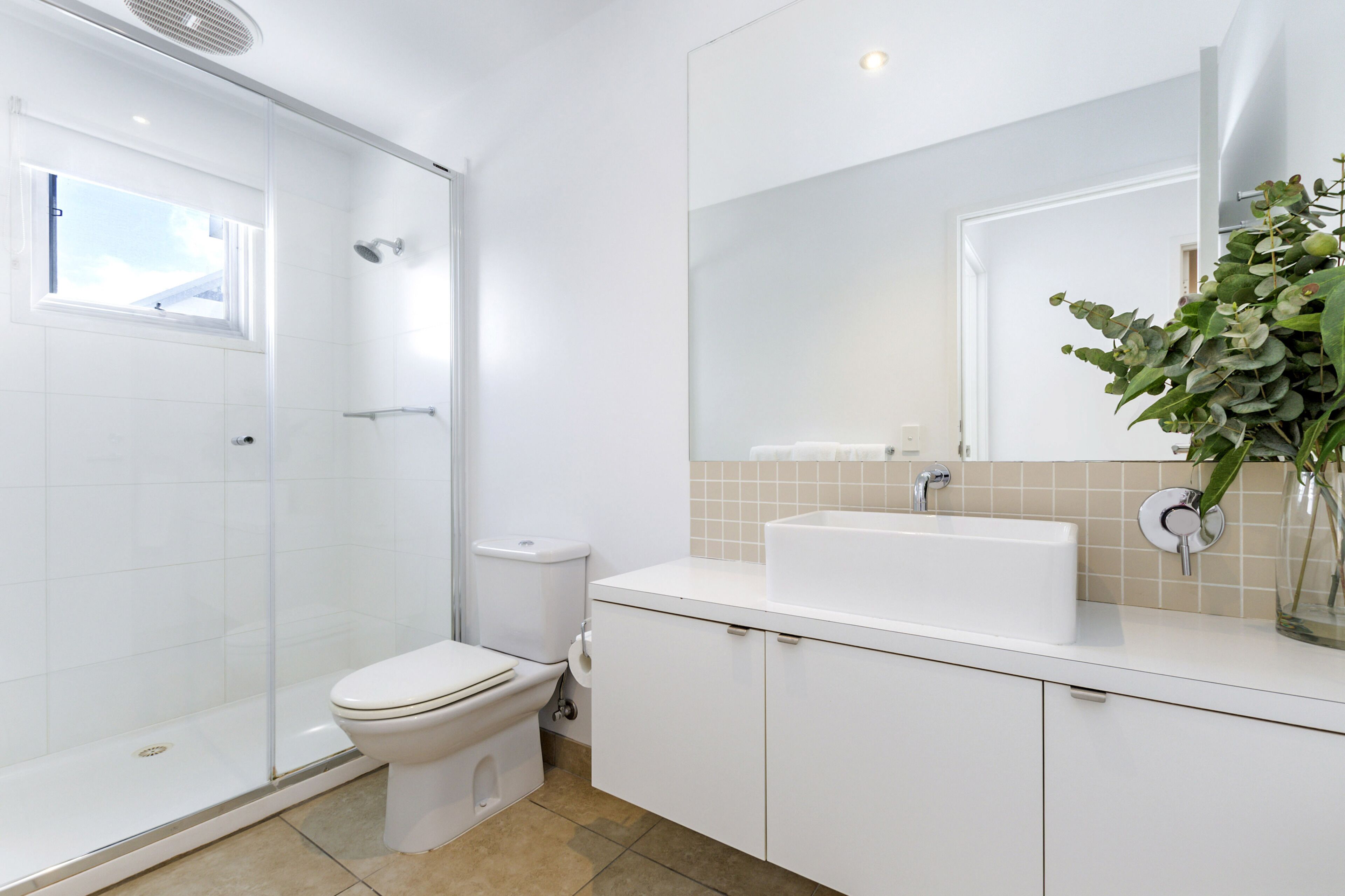 Un baño moderno con cabina de ducha de vidrio, inodoro, lavabo y espejo.