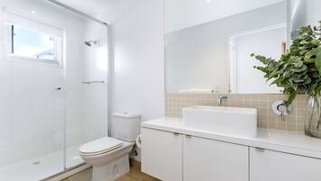 Un baño moderno con cabina de ducha de vidrio, inodoro, lavabo y espejo.