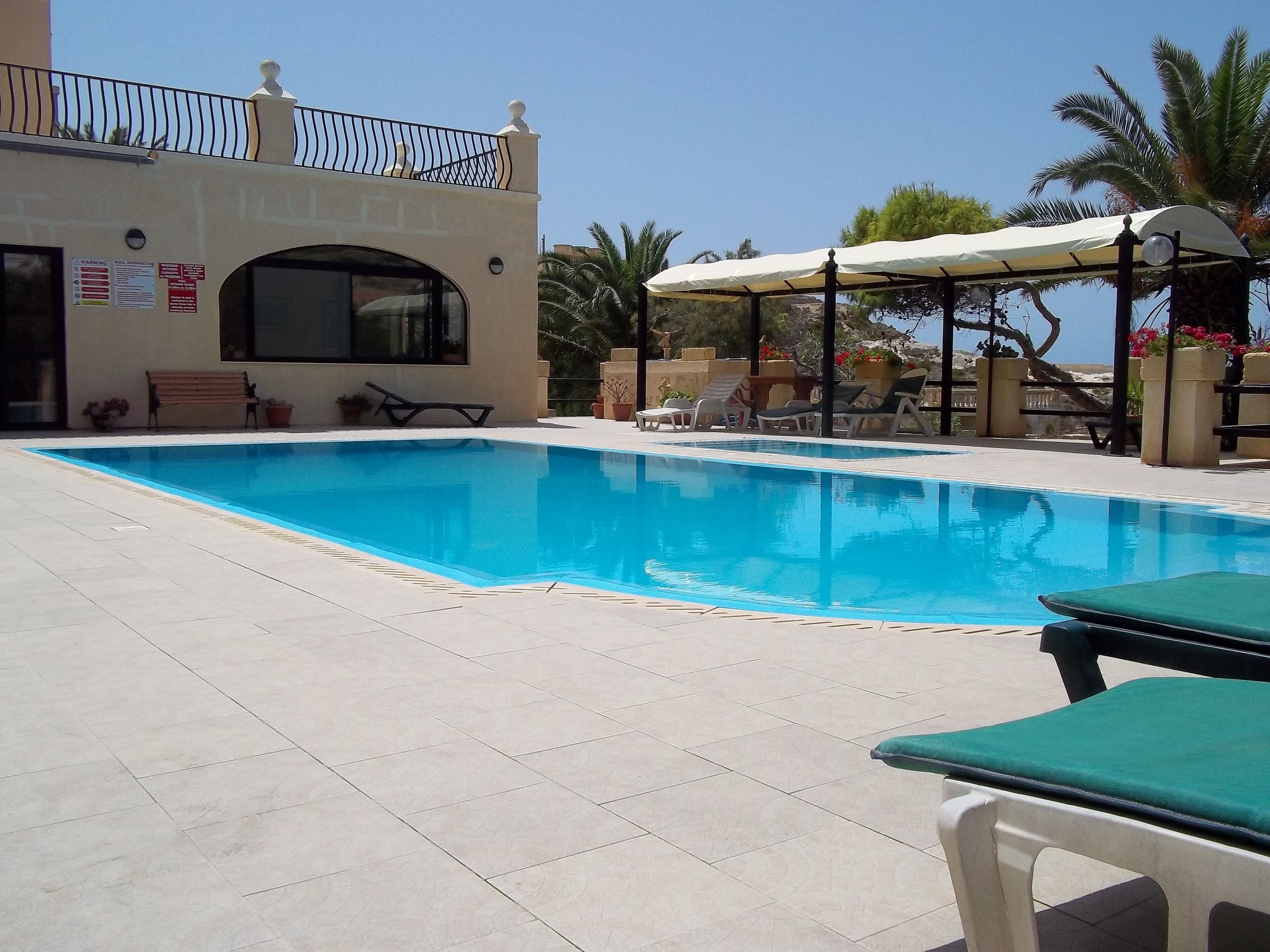 Ein Pool mit Liegestühlen und einer überdachten Sitzgruppe.