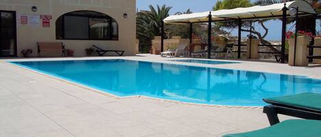 Ein Pool mit Liegestühlen und einer überdachten Sitzgruppe.