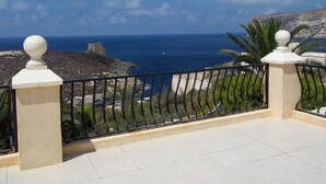 Un balcon avec vue sur la mer et un paysage rocheux.