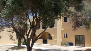 Un bâtiment à la façade beige, doté de nombreux balcons, avec un arbre au premier plan.