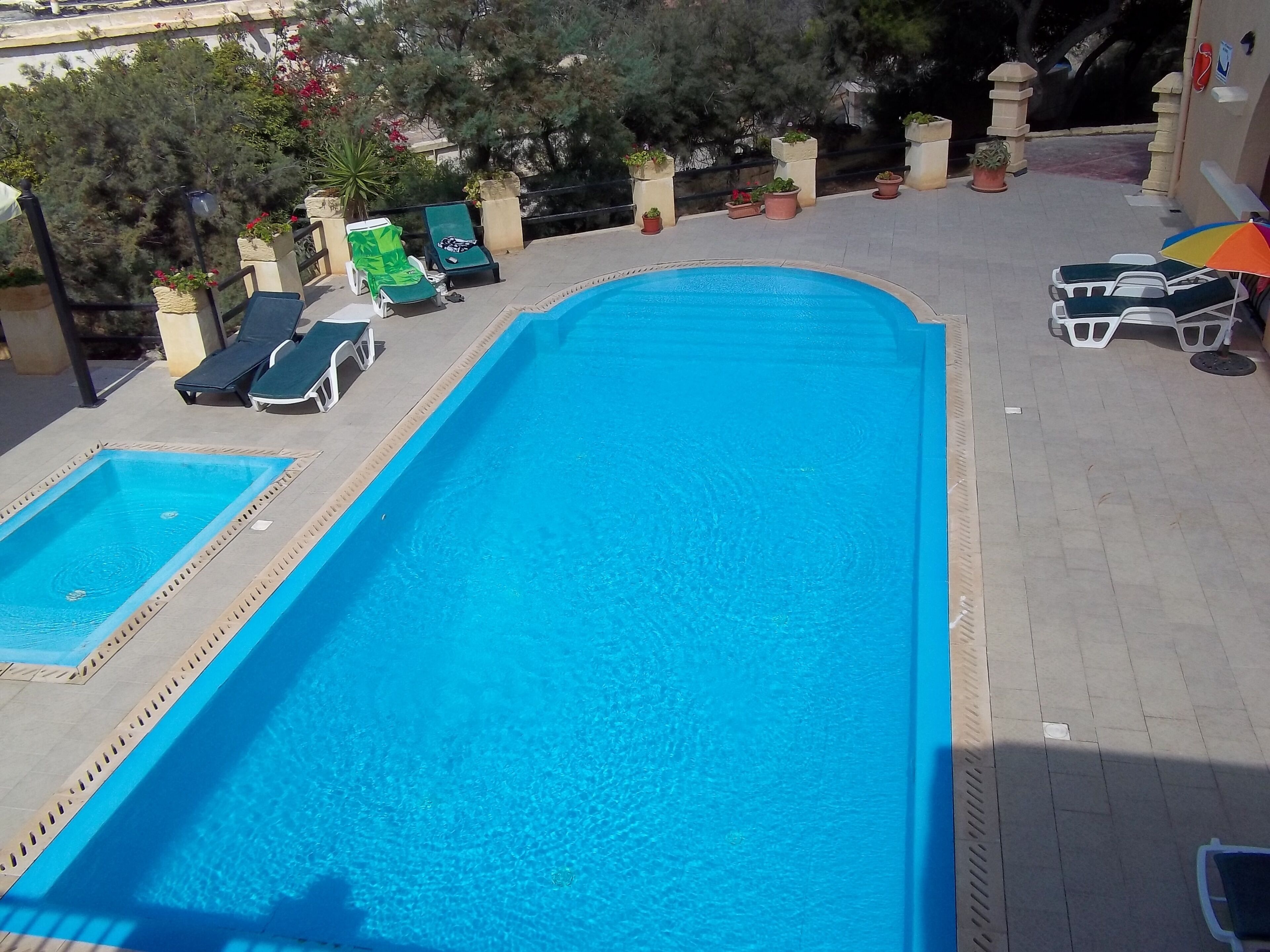 A swimming pool with lounge chairs and potted plants around it.