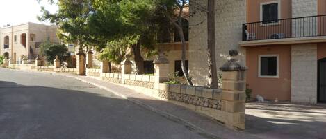 A street with a row of buildings, stone walls, and trees.