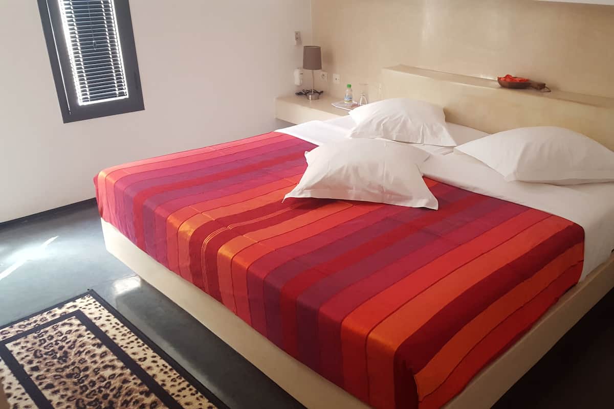 A bed with a red and white striped bedspread, white pillows, and a wooden headboard.