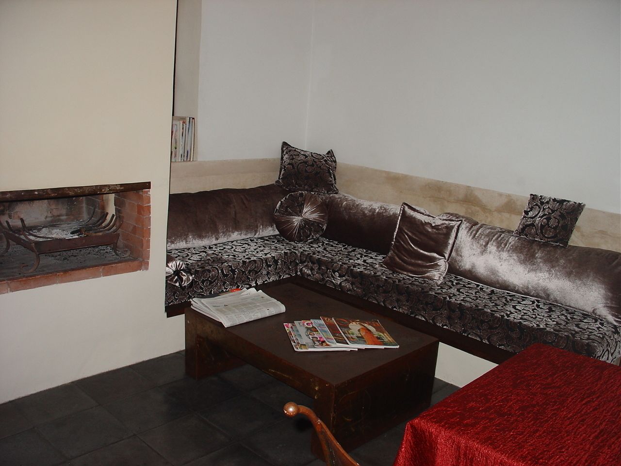 A living room with a brown sofa, a wooden coffee table, and a red tablecloth.