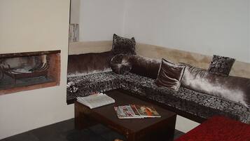 A living room with a brown sofa, a wooden coffee table, and a red tablecloth.