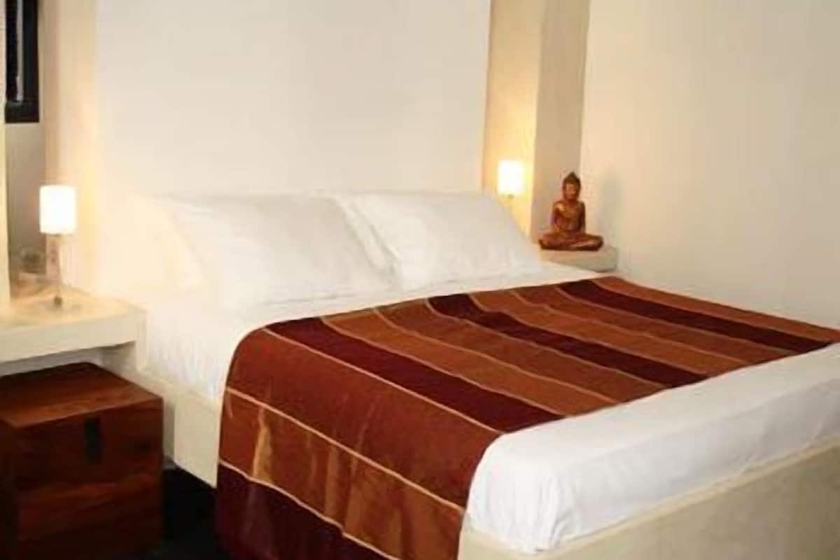 A hotel room with a bed, a nightstand, a lamp, and a statue.