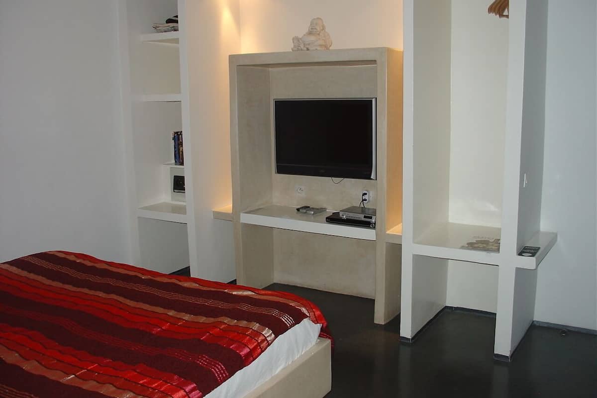 A bedroom with a bed, a TV, and built-in shelving.