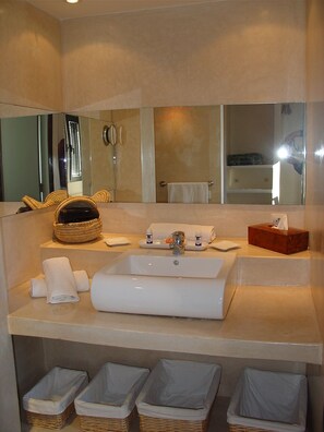 A bathroom with a large sink, a mirror, a towel rack, and a basket. - La Villa & Spa (El Jadida)