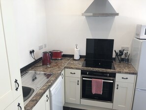 Una cocina compacta con lavamanos, estufa, horno y microondas.