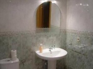 A bathroom with a round sink, a mirror, and a toilet. - Hostal Emilio (Madrid)